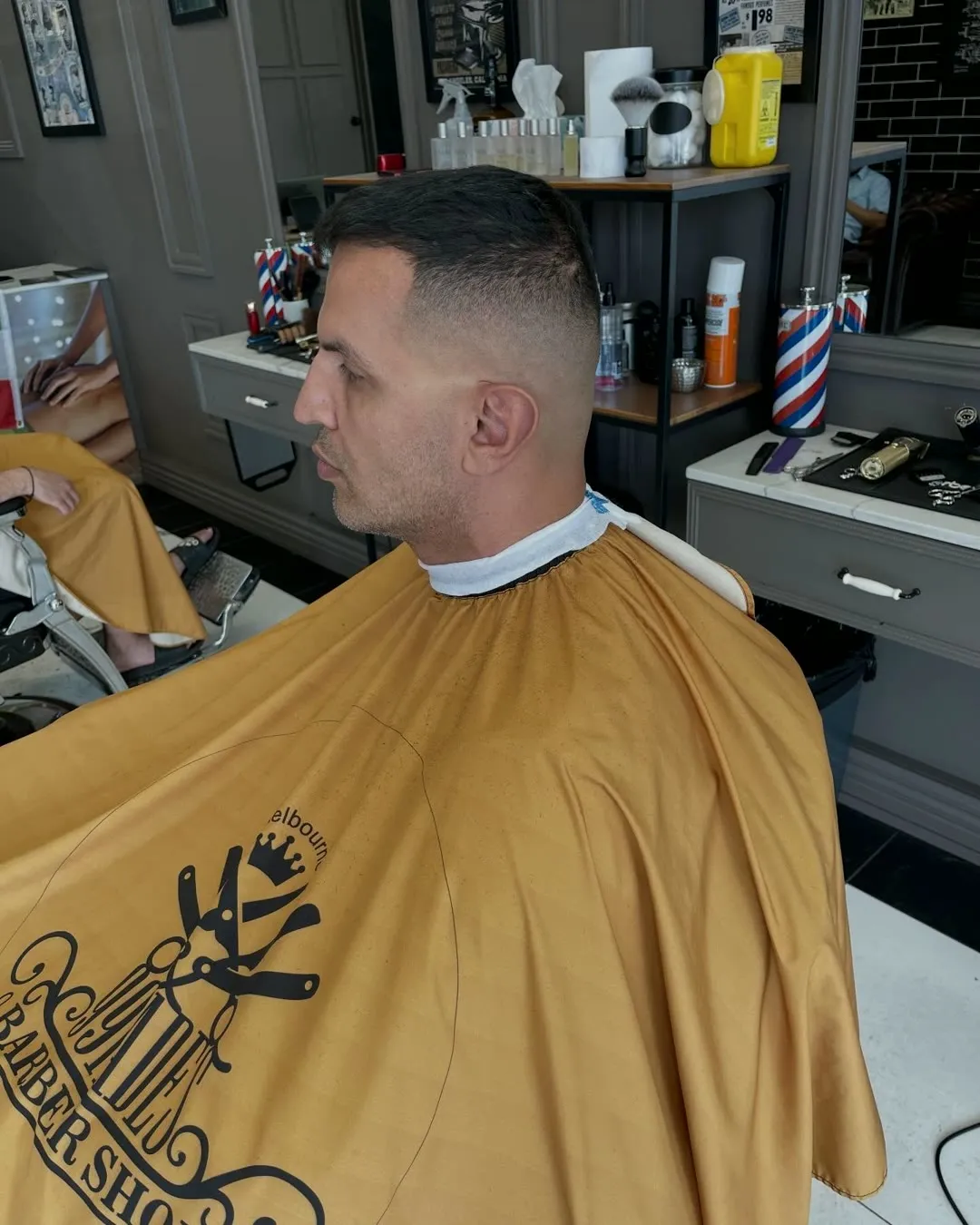 High skin fade, client in a gold cape in the shop